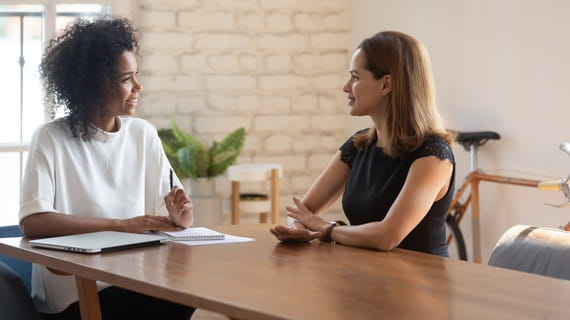Lors d’un entretien d’embauche, deux femmes discutent autour d’une table sur les modalités du poste.