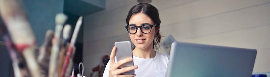 Une jeune femme lit sur son mobile un article sur les différences entre CDD et intérim.